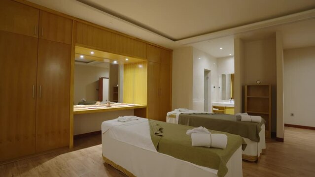 Interior of empty spa salon room with massage table, aroma lamps, towels. Beauty retreat centre with products for skin care procedures and therapy. No people, candle lights.