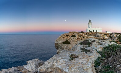 view of the Cap de Cavalleria Lighthouse on Menorca at sunset with a full moon rising