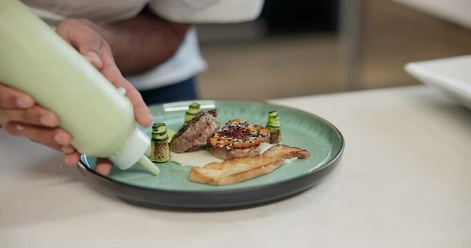 Chef, plate and hands of man with bottle in kitchen for catering service, fine dining or prepare dish. Hospitality, presentation and person for cooking meal, food industry or dinner in restaurant