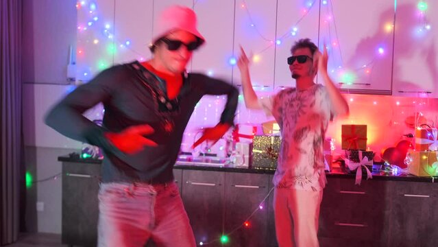 Crazy guys students friends dancing at college party moving to the rhythm of the music in black glasses having fun at the neon lights festival.