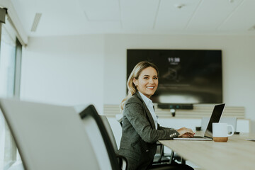 Young professional woman working on laptop in a bright office midday