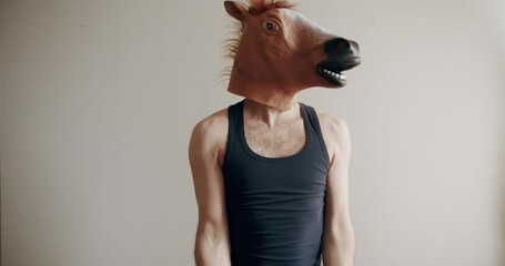 Funny man with horse mask doing exercise with weights for hand training on the white background at home. Concept of Funny Health and Fitness. Humorous stretches. Funny home workout.