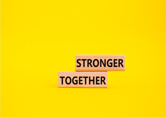 Stronger together symbol. Wooden blocks with words Stronger together. Beautiful yellow background. Stronger together concept. Copy space.