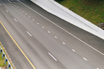 Empty Four-Lane Freeway with Dashed Lines and Grass Hillside