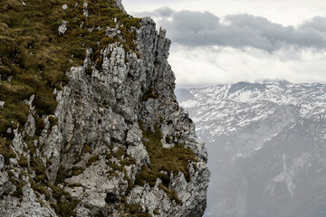 The view depicts a mountain towering over a valley, with lush greenery contrasting the rugged...