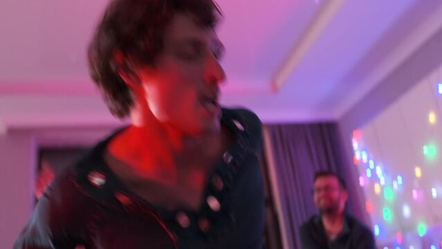 Group of friends line dancing  together at home party, dynamic movements of friends getting down dance to beats music in neon lights. Close up.