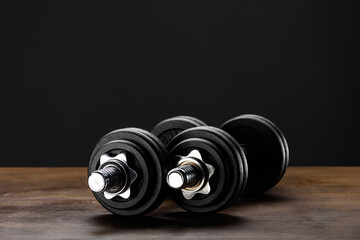 Closeup shot of two dumbells placed on dark wooden surface