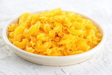 Dry, raw pasta Creste Di Gallo in a plate.