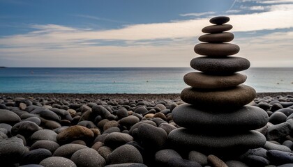 pile of smooth stones stacked on a pebbly beach symbolizing balance and stability with the ocean backdrop