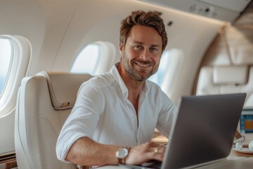 A man is sitting in a plane with a laptop in front of him