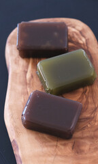 Traditional Japanese yokan jelly cake, adzuki red bean, chestnut and matcha green tea flavoured, on wood board on black background