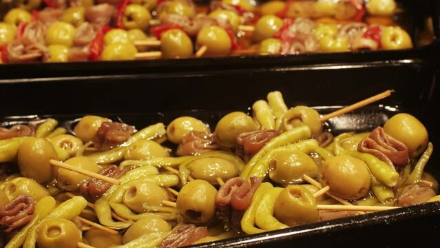 Marinated green olives in spicy sauce with fish and cheese tapas, spanish traditional food, ideal for Mediterranean dish or snack, market in barcelona.
