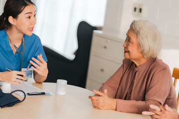 Happy Senior Asian Woman Receives Medical Care at Home, Doctor or Caregiver Nurse Provide Support Assistance, Enhancing Healthcare Services for Elderly Patients Retirement