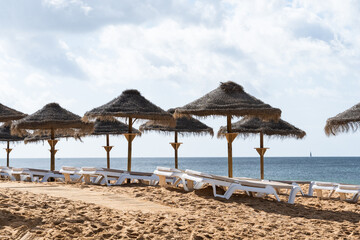 Straw chairs and umbrella. Praia do Peneco beach, Albufeira, Algarve, Portugal. Praia dos...