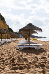 Straw chairs and umbrella. Praia do Peneco beach, Albufeira, Algarve, Portugal. Praia dos...