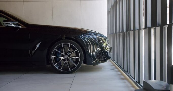 A sleek black luxury sports car parked in a contemporary building, showcasing modern automotive design and architecture. Luxury Sports Car Parked Elegantly Inside Modern Building