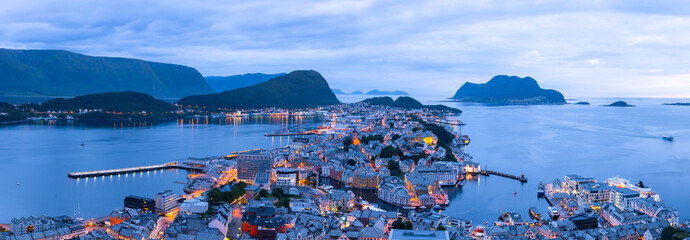 Panorama of Norwegian port town Alesund in evening time. Norway cityscape with fjord, islands, mountains, boats and typical norwegian houses