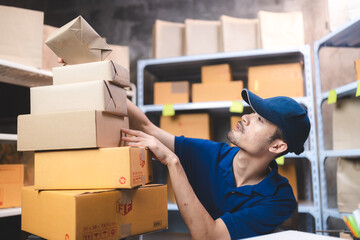 A man in a blue shirt is reaching for a box on top of a stack of boxes