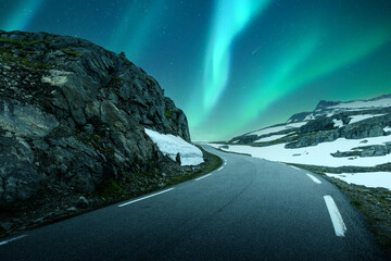 Aurora borealis Northern lights in night winter sky above the famous mountain snowy road in Norway