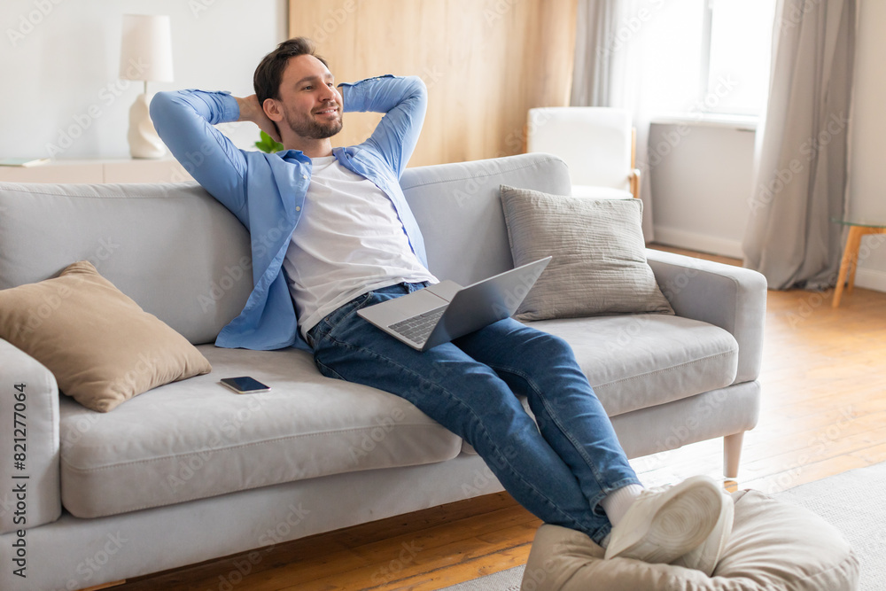 Aufkleber A middle-aged man is seen relaxing on a comfortable couch, engrossed in his laptop screen. He appears calm and focused as he works or browses the internet in a cozy indoor setting.