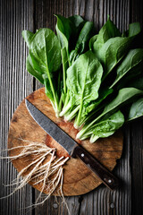 Cutting fresh green spinach leaves on a wooden board with old rustic knife. Food photography