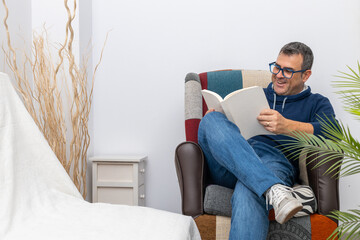 young adult boy reading a book on a sofa