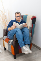  young adult boy reading a book on a sofa