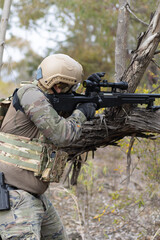 Fototapeta premium Soldier airsoft player dressed in camouflage uniform wielding a sniper rifle