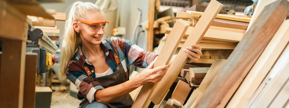 Attractive middle aged woman carpenter designer works with ruler, make notches on the tree in workshop. Image of modern femininity. Concept of professionally motivated women