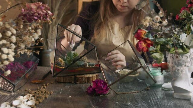 In the gardener's workshop, she creates an aesthetic and environmentally friendly element of interior design with her own hands - a florarium. Close up. Slow motion. 4k