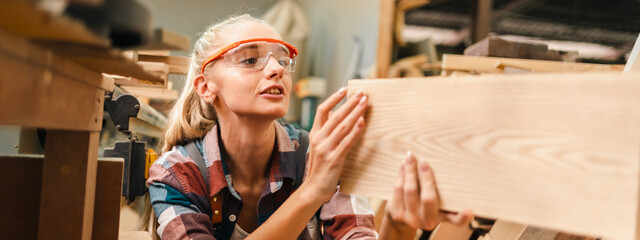 Attractive middle aged woman carpenter designer works with ruler, make notches on the tree in...