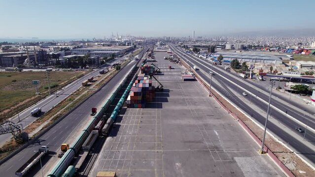 Cargo containers, trucks and loading reach-stackers at industrial area. Cargo logistics terminal aerial view