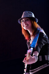 Auburn-haired woman plays guitar with joyful expression