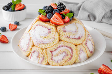 Charlotte Royale Cake with strawberry cream inside and decorated fresh berries. Delicious summer cake.