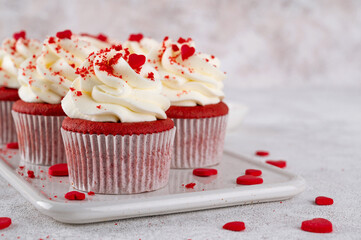 Red velvet cupcakes with cream cheese frosting and red sugar hearts. Delicious dessert for Valentines day. Selective focus, copy space.