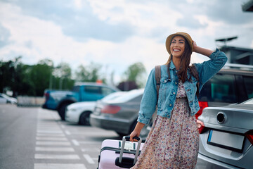 Young happy woman with suitcase going to airport terminal.