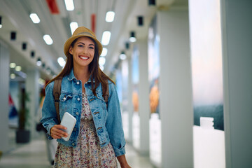 Young happy woman walking through departure area at airport.