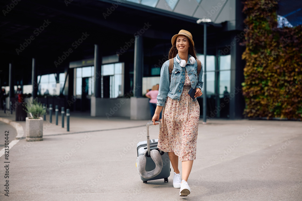 Wall mural Young happy woman arriving at  airport.