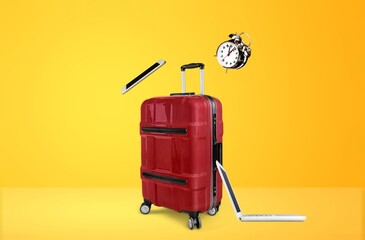 Travel suitcase and set of gadgets on background