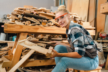 Attractive middle aged woman carpenter designer works with ruler, make notches on the tree in...