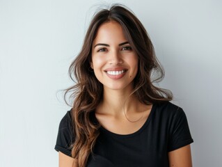 Fototapeta premium Beautiful natural brunette woman, smiling and looking in camera with white teeth. Close-up portrait of cute female woman in black t-shirt on white background. 