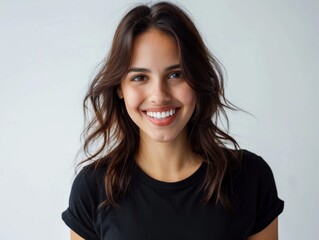 Obraz premium Beautiful natural brunette woman, smiling and looking in camera with white teeth. Close-up portrait of cute female woman in black t-shirt on white background. 