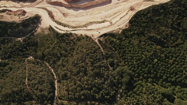 Overhead shot of a vast limestone quarry with winding paths and industrial equipment in a natural setting.