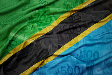 waving colorful national flag of tanzania on a euro money banknotes background. finance concept.