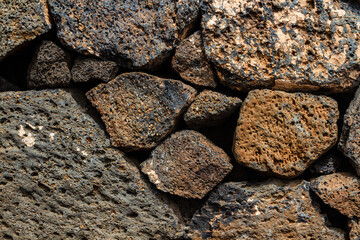Close-up. Background. Wall of large and small natural volcanic stones.