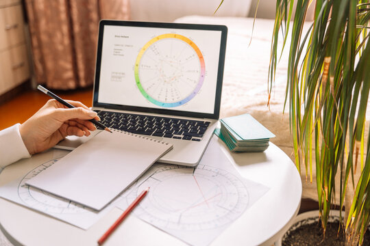 An astrologer makes a natal chart using a laptop.