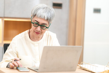 Late-night freelancer, Dedicated Asian woman working overtime on laptop computer, meeting deadlines in the sleepy Night, Businesswoman burning the midnight to working hard, sleep at working desk