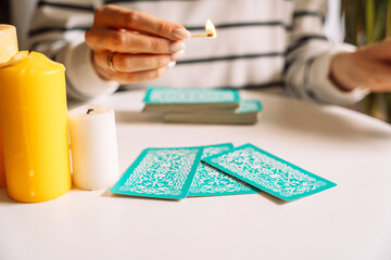 Tarot reader holding a burning match over tarot cards.