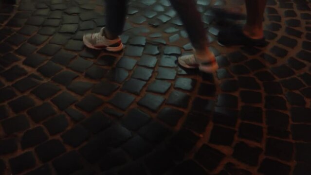 feet of people walking on the paving stones in the evening