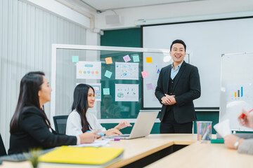 Asian businessman present start up project to expert investor, Teamwork group of multicultural business team solving problems, discussing business idea with skyscraper at modern business lounge